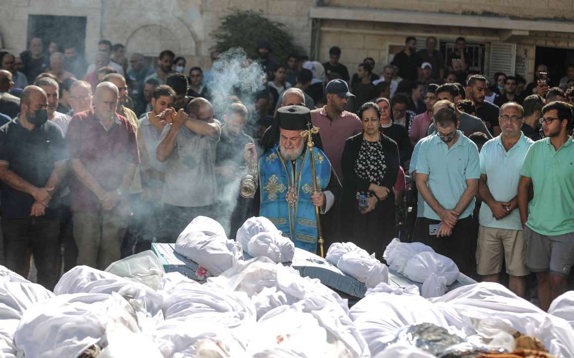 غزّيون يشاركون في مراسم تشييع فلسطينيين مسيحيين قُتلوا في هجمات شنتها قوات الجيش الإسرائيلي على كنيسة القديس بورفيريوس في مدينة غزة.