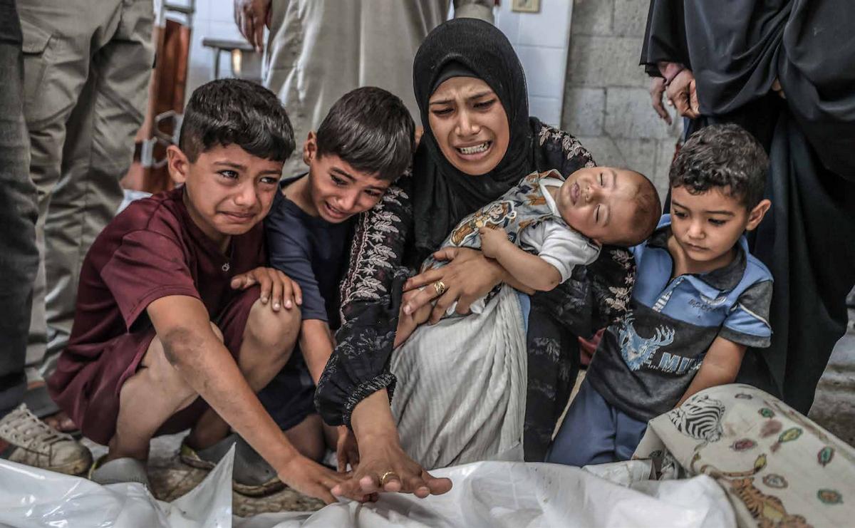 نقل جثامين لفلسطينيين استشهدوا جراء هجوم الجيش الإسرائيلي على مستشفى شهداء الأقصى في دير البلح، تمهيدًا لدفنهم. تجمع لذوي الضحايا حول الجثامين، غارقين في الحزن والألم، أثناء توديعهم أحباءهم الراحلين. 