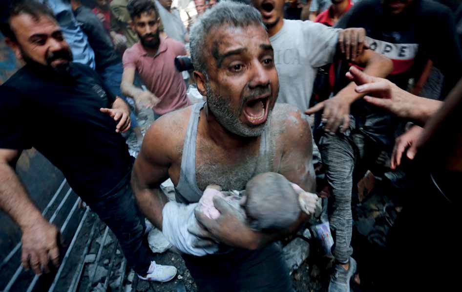 فلسطيني يحمل جثة طفل رضيع قتل في هجوم شنته القوات الإسرائيلية على مخيم الشاطئ للاجئين.