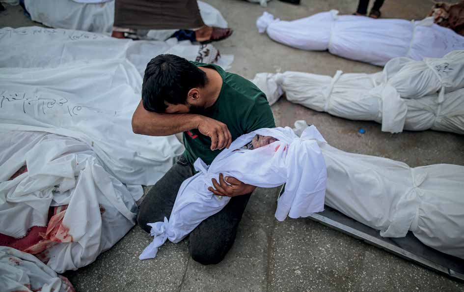 نقل جثامين ضحايا سقطوا خلال هجمات الجيش الإسرائيلي من ثلاجة الموتى في مستشفى شهداء الأقصى بمدينة دير البلح لمواراتها الثرى. أب ينظر بحزن شديد إلى ابنه للمرة الأخيرة.