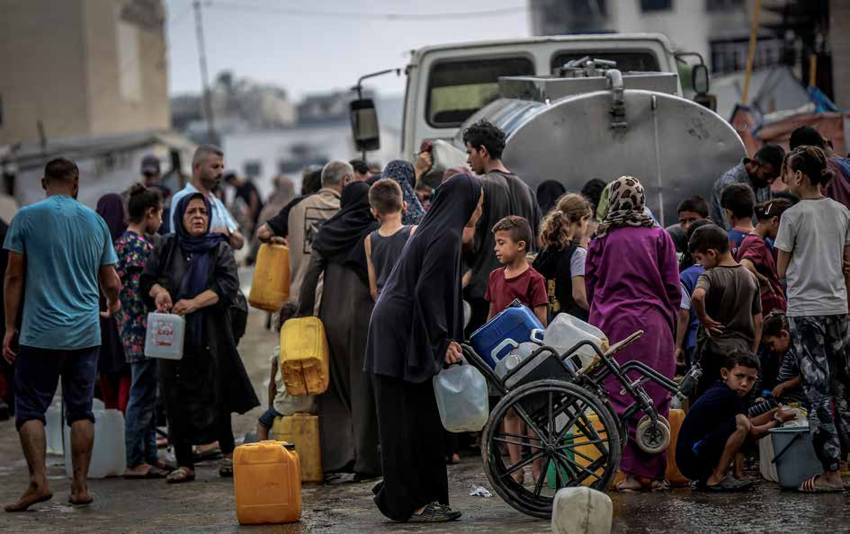 يصطفّ الفلسطينيون وهم يحملون عبوات بلاستيكية للحصول على المياه من شاحنة توزيع، في ظل أزمة مياه خانقة ناجمة عن الهجمات الإسرائيلية في مدينة غزة. ومنذ أكثر من 20 شهرًا، خسر العديد من الفلسطينيين منازلهم جراء القصف، ويقيمون اليوم في خيام بسيطة بجانب المباني المدمرة أو المتضررة. وتواجه العائلات النازحة صعوبات كبيرة في الحصول على المأوى، والغذاء، والمياه النظيفة، ومواد النظافة، والرعاية الصحية. أما الأطفال، فيحاولون التمسّك بالحياة من خلال ألعاب بسيطة يمارسونها بين الخيام والركام، في ظل أجواء الحرب.