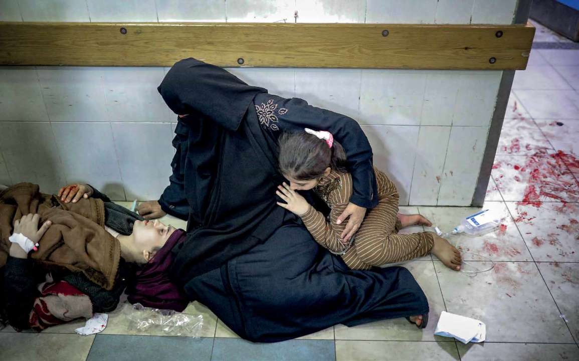 أم فلسطينية، بصحبة ابنتها الصغيرة، في مستشفى ناصر الطبي، تنتظر بجانب ابنتها الكبرى التي أصيبت في هجوم شنه الجيش الإسرائيلي.