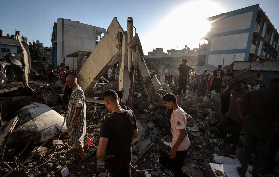 الجيش الإسرائيلي يشن هجومًا على مدرسة تابعة لوكالة الأمم المتحدة لإغاثة وتشغيل اللاجئين الفلسطينيين (الأونروا)، والتي كانت تستخدم كمركز إيواء في مخيم النصيرات للاجئين وسط قطاع غزة. فلسطينيون من سكان المنطقة يتفقدون أنقاض المدرسة التي تعرضت لأضرار جسيمة نتيجة الهجوم.