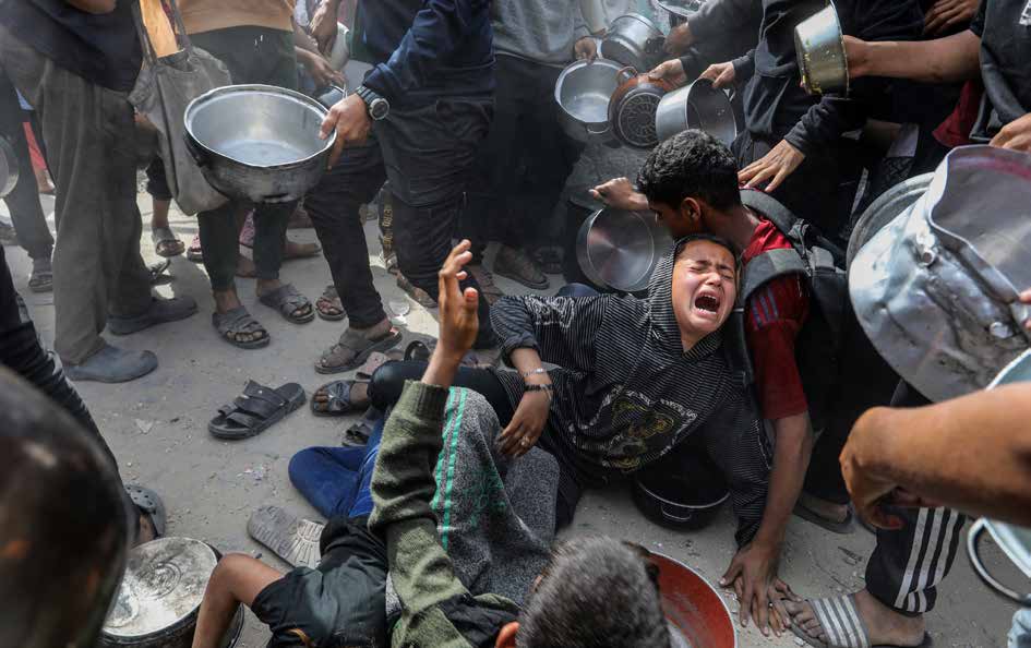 As Israel’s relentless and devastating attacks on the blockaded Gaza Strip continue, the humanitarian crisis deepens under a total embargo. In Khan Younis, southern Gaza, aid groups distribute hot meals to displaced Palestinians. Crowds, including many children, surge forward in desperation to receive food.