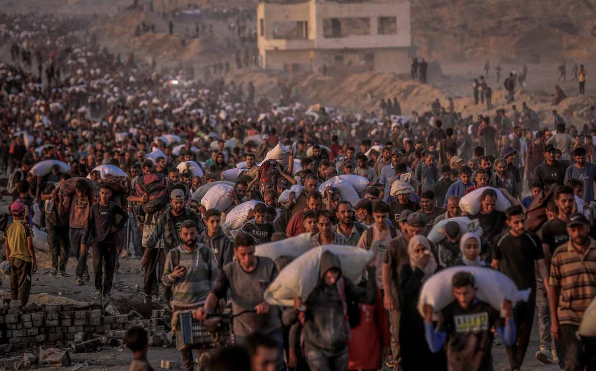 Palestinians rush to a relief center set up along the Coastal Road in the Sudaniyya area of Gaza City to receive food packages.